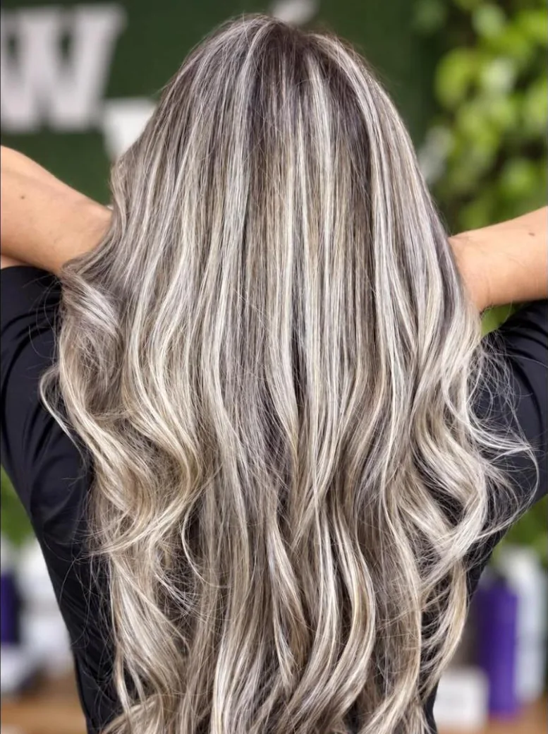 Cabelo longo com mechas claras sobre base grisalha, visto de costas